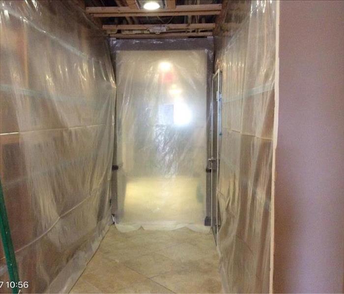 Hallway with poly sheeting covering the walls and the exposed ceiling support beams