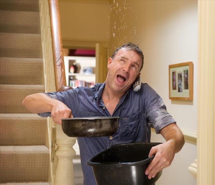 man catching leaking water from ceiling